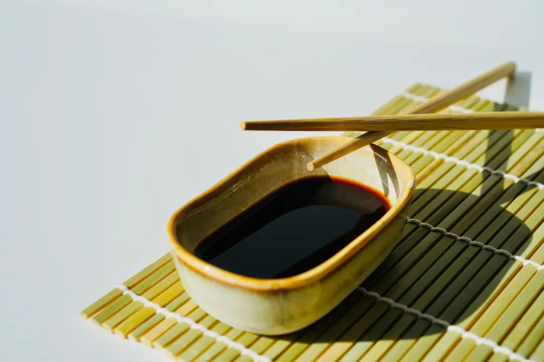 A soy sauce dish resting on a bamboo mat