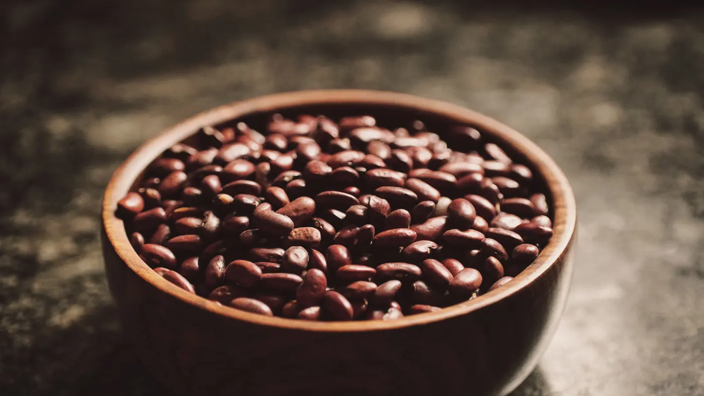 A wooden bowl of dark red beans