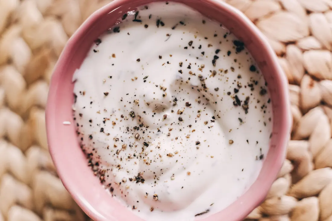 A bowl of thick white sauce with cracked pepper