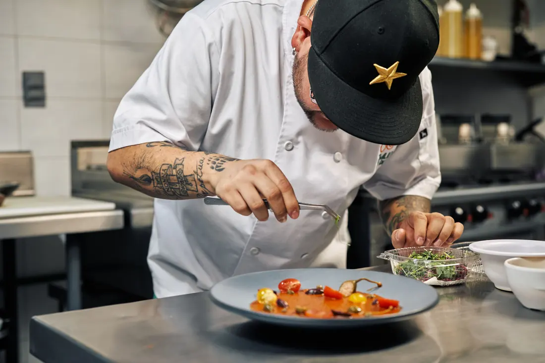 A cook plating a dish in a kitchen