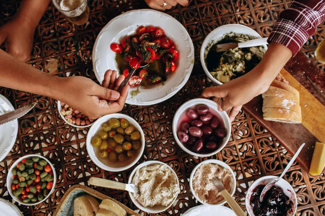 Hands reaching across a table of shared dishes