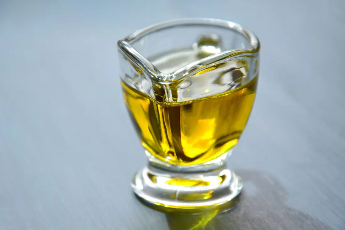 A pale golden oil in a glass jug