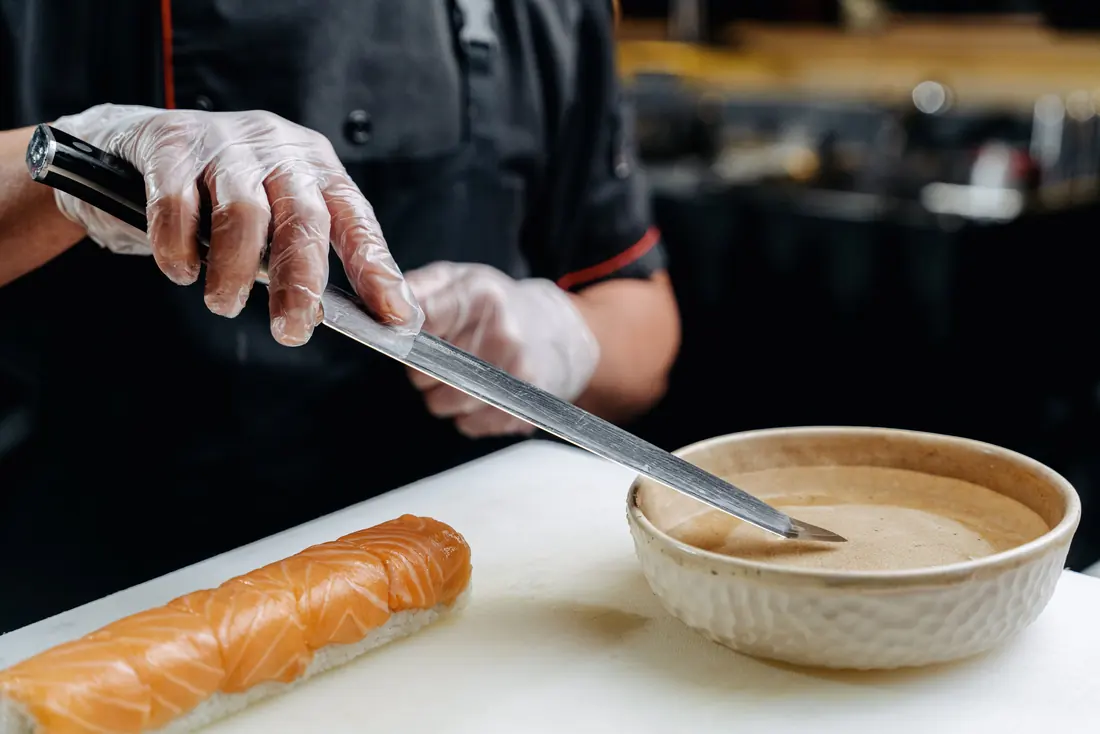 A cook working beside a rolled sushi log