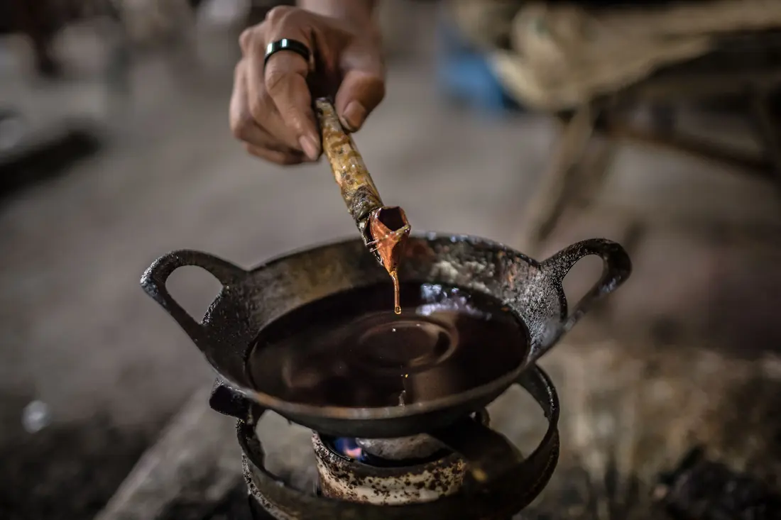 A thick dark mixture being worked in a pan