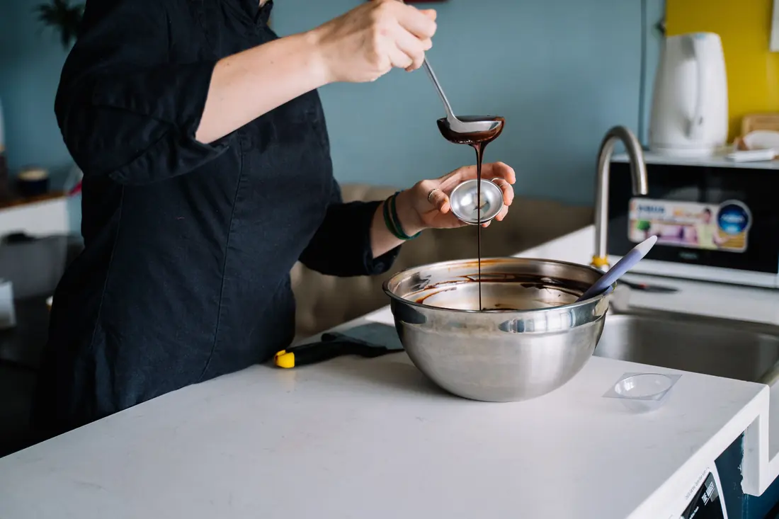 A dark liquid being poured into a bowl