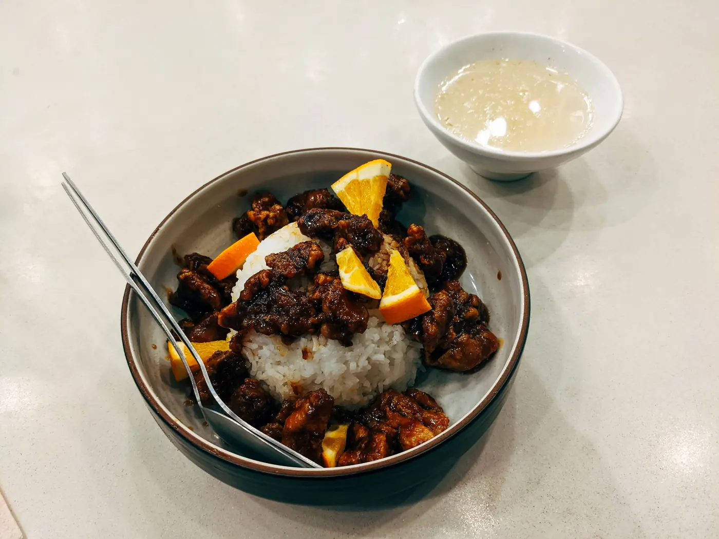 A rice bowl beside a small dish of sauce