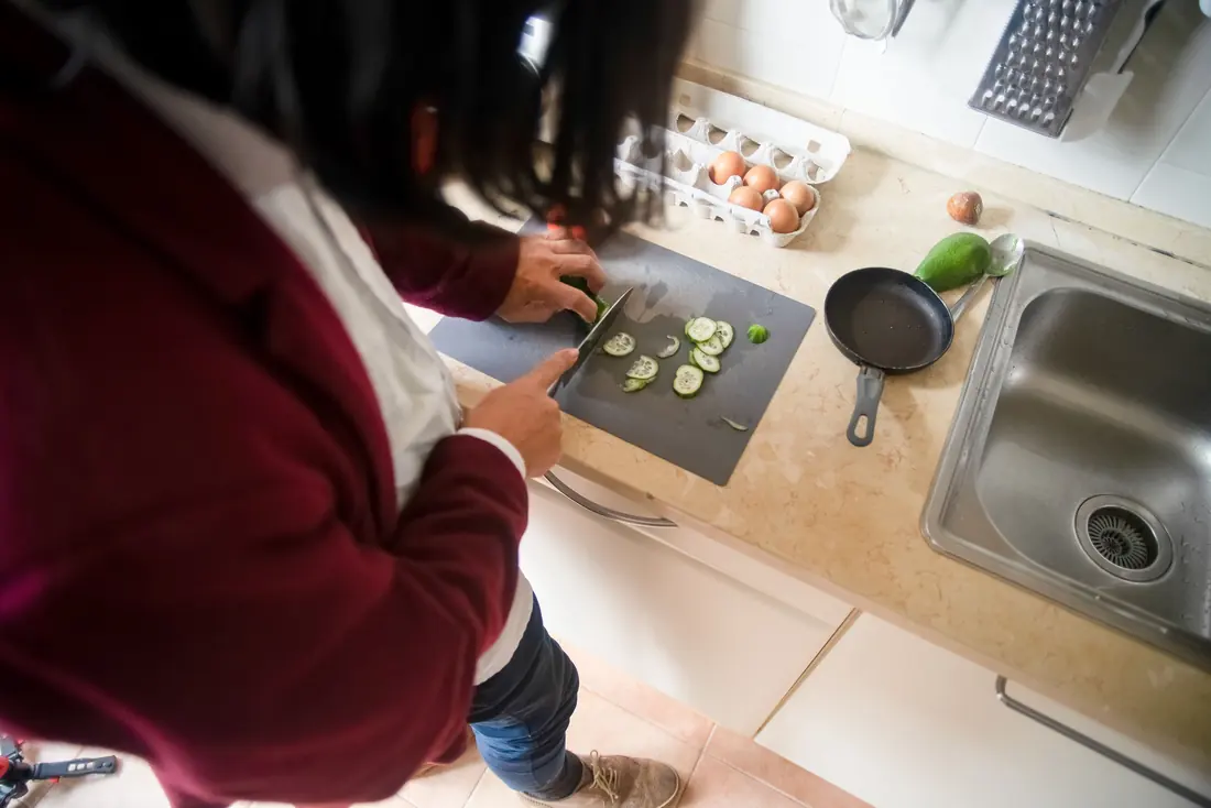 Cucumber being sliced in a kitchen