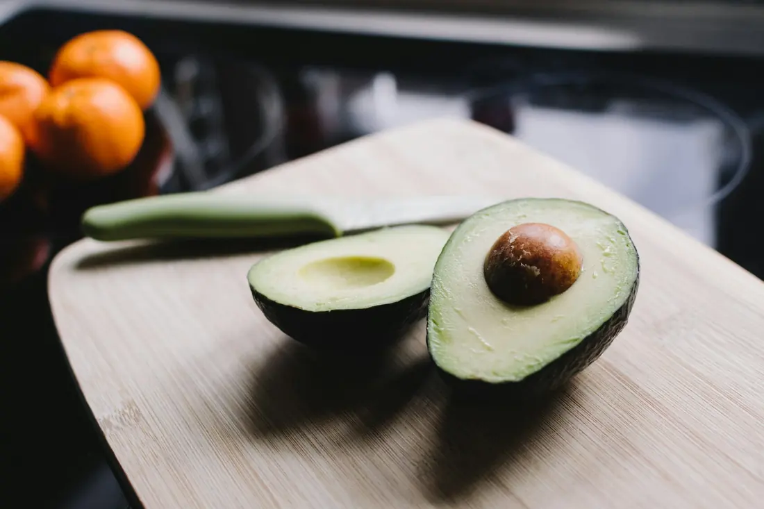 A halved avocado on a chopping board