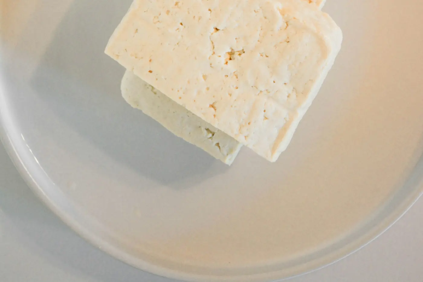 A block of fresh white tofu on a wooden board