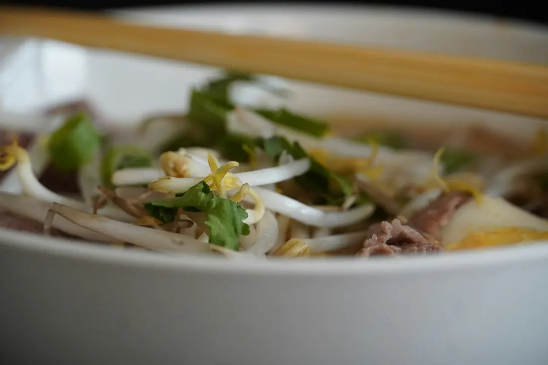 Sliced beef and noodles in a bowl of pho broth
