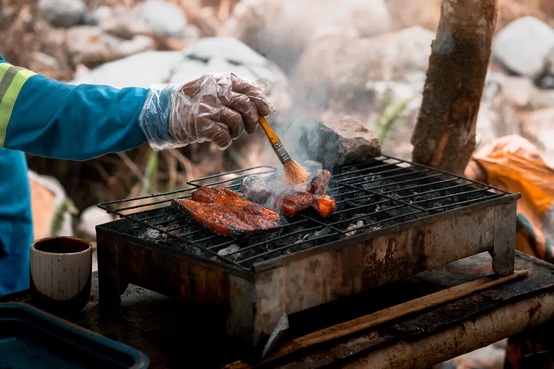 Glaze being brushed onto food on a grill