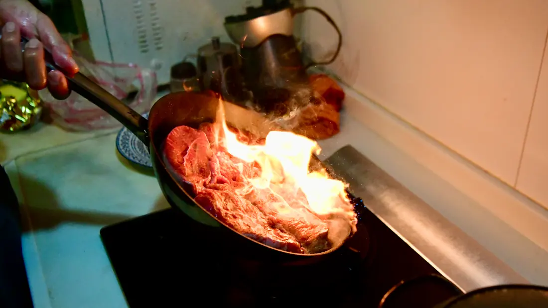 Meat cooking in a pan over high heat