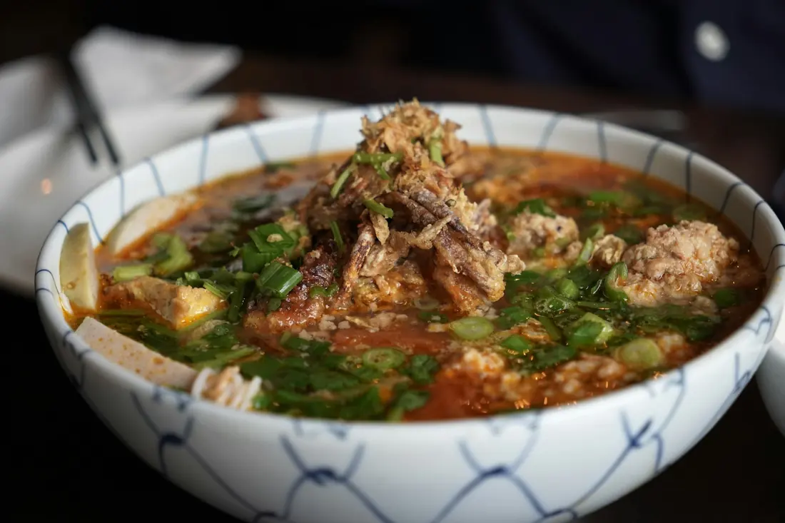 A noodle soup bowl served with fresh herbs and scallions