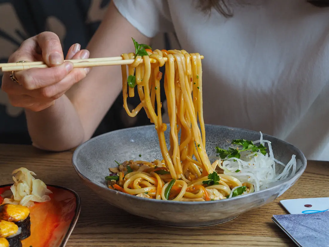 Chopsticks lifting food from a bowl