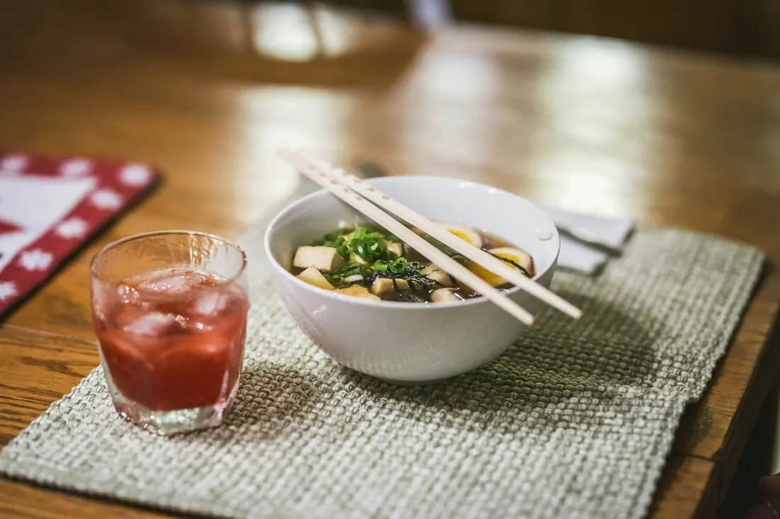A bowl of noodle soup set at a table