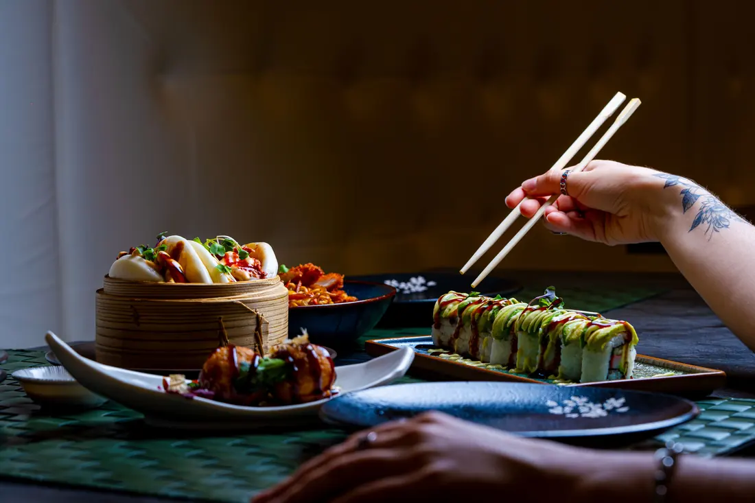 Chopsticks lifting a piece from a shared plate