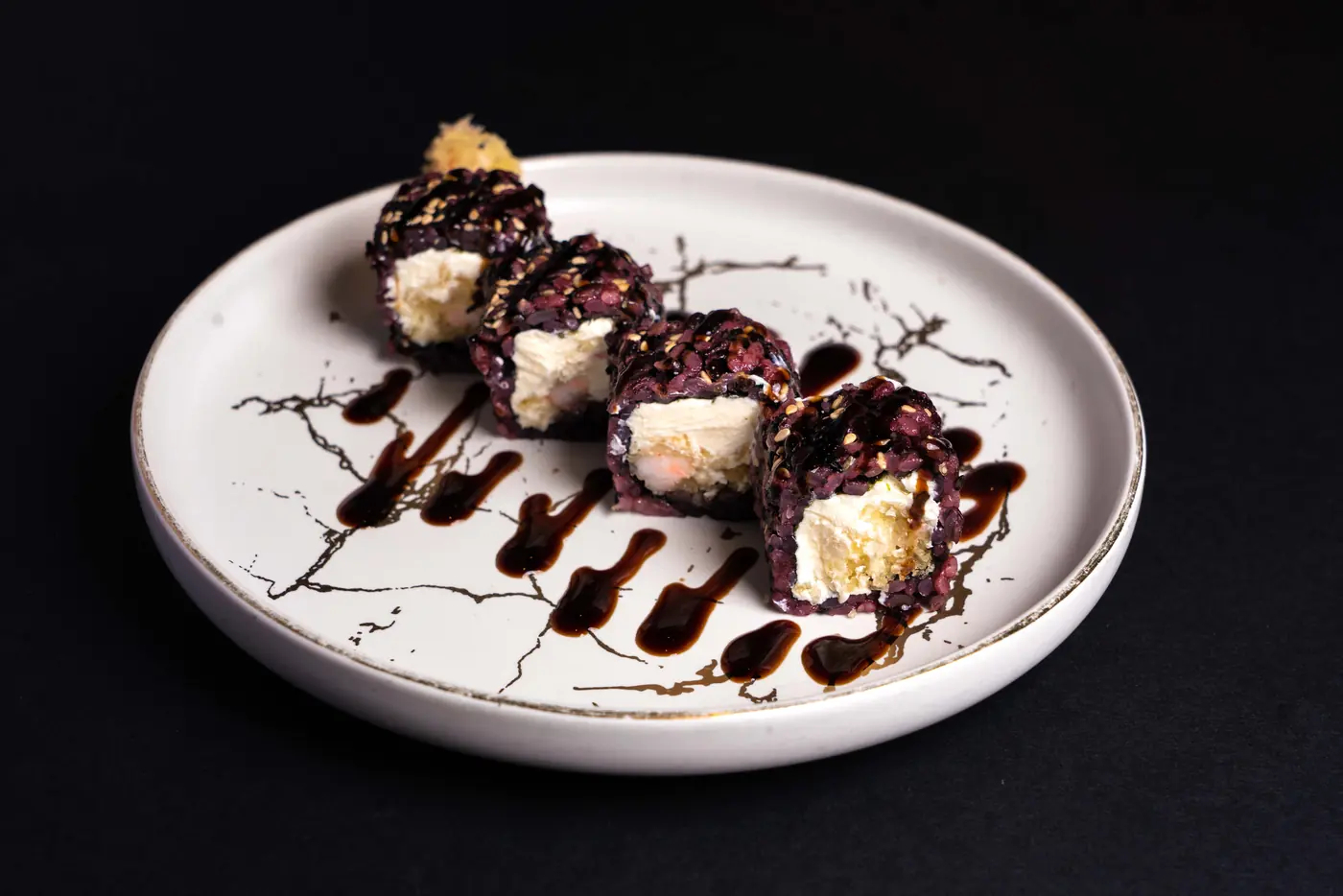Dark glaze drizzled around plated rolls