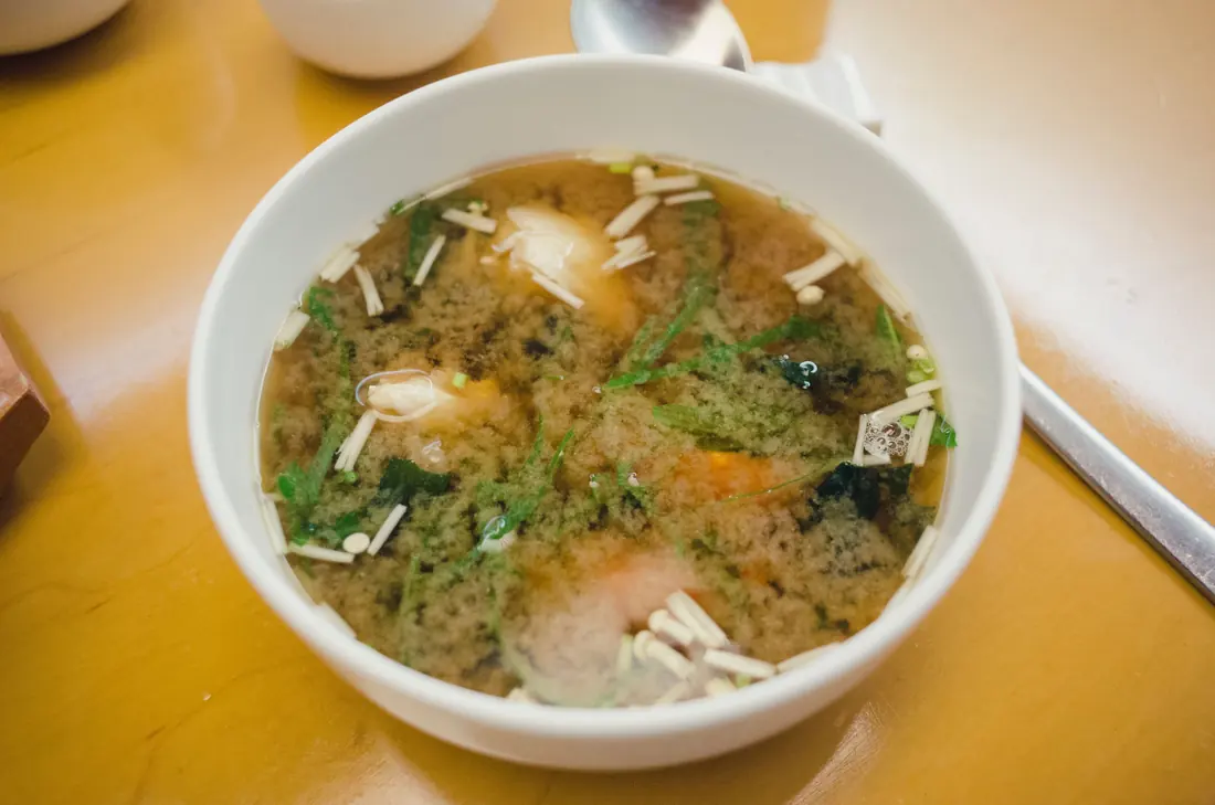 A bowl of miso soup with tofu and seaweed