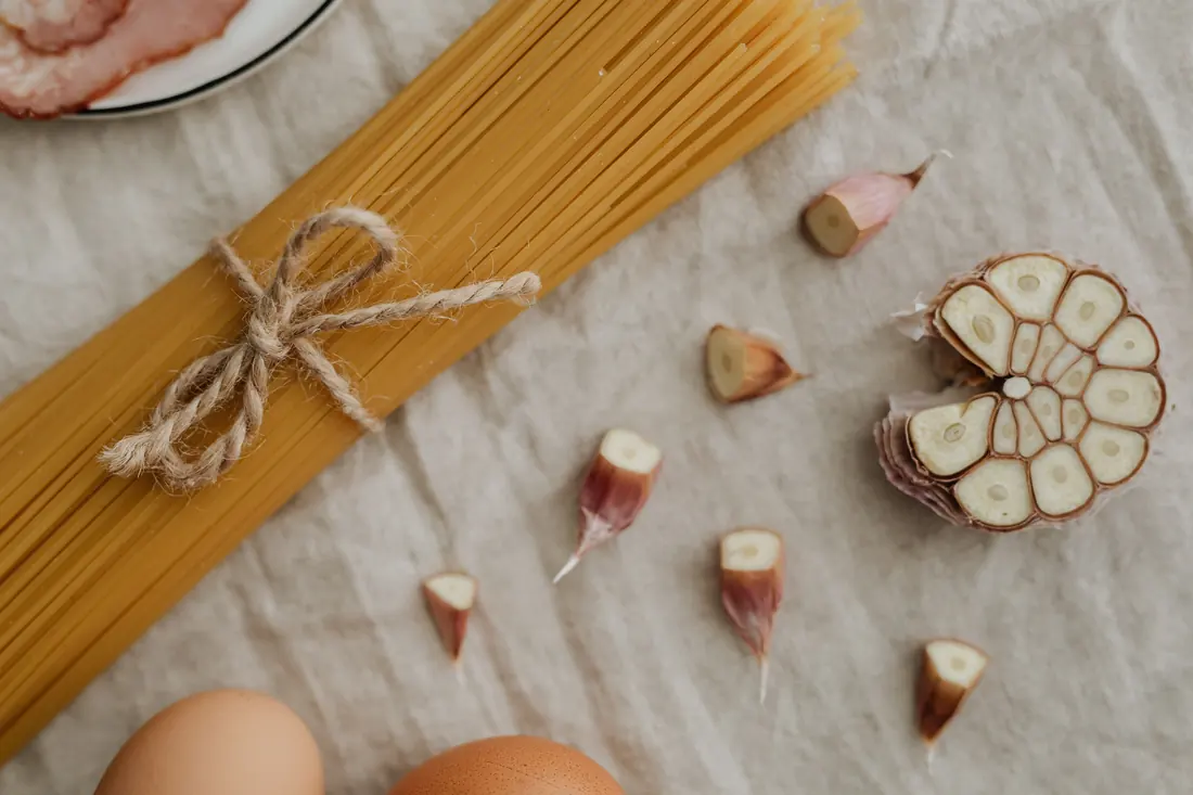 Dried noodles bundled beside eggs and garlic