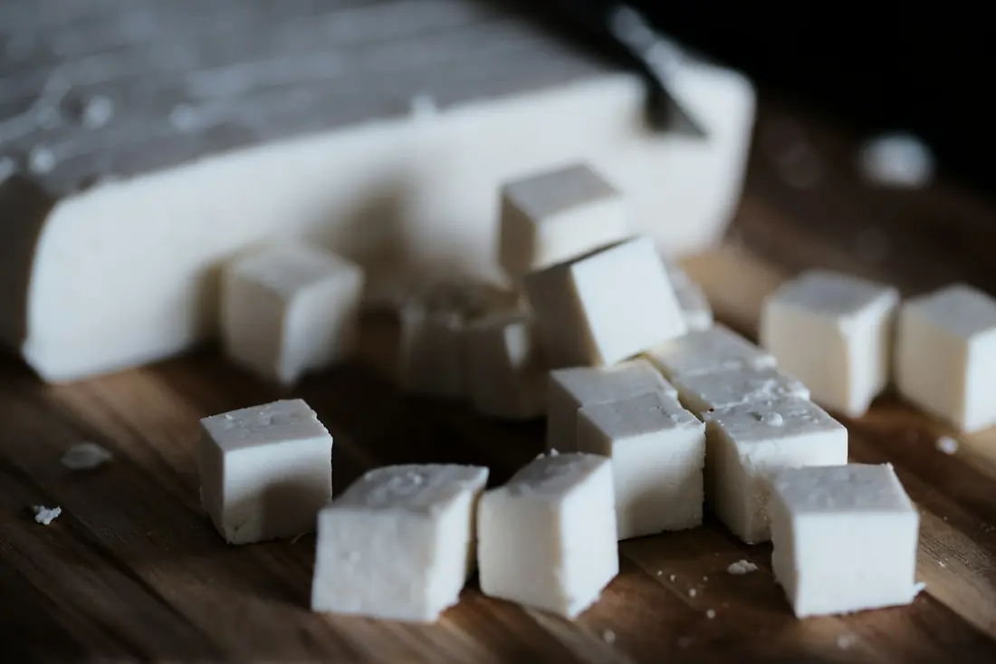 Firm tofu being sliced on a board