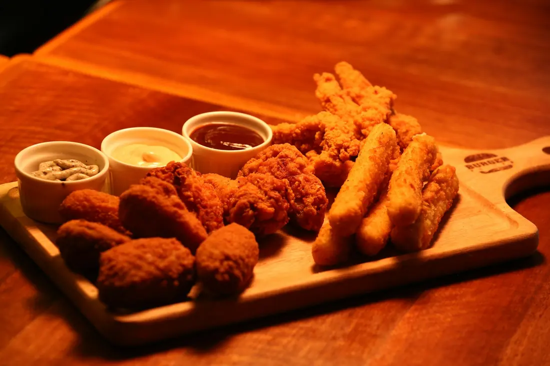 Fried finger food with dipping sauces on a board