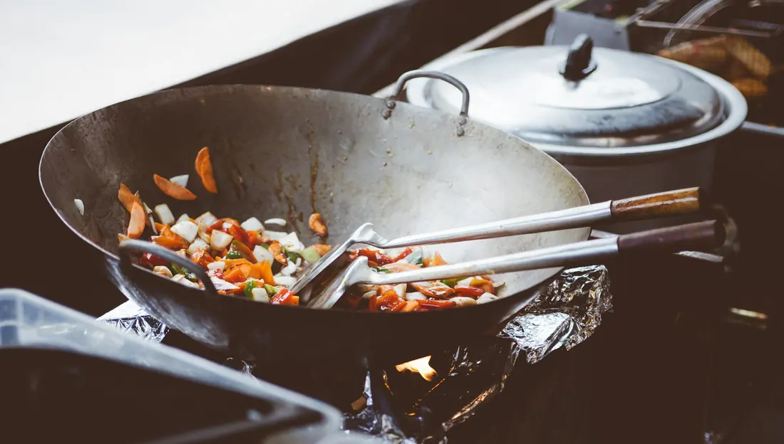 Fried rice being turned on a griddle with metal spatulas