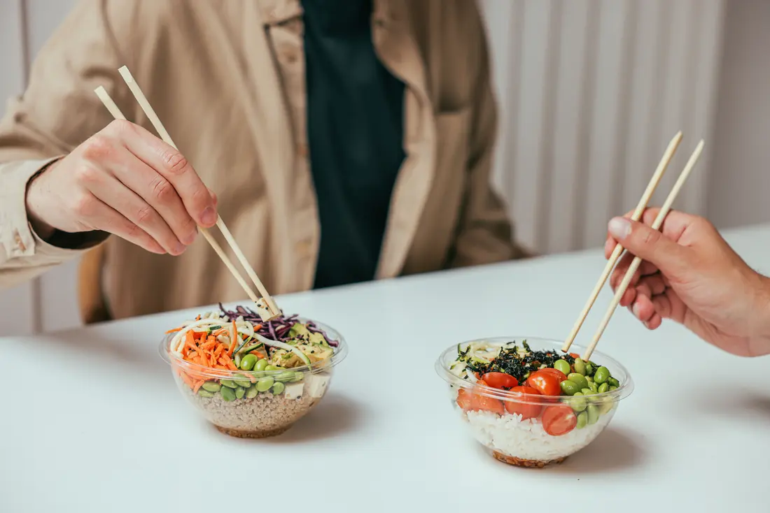 Hands using chopsticks over two bowls
