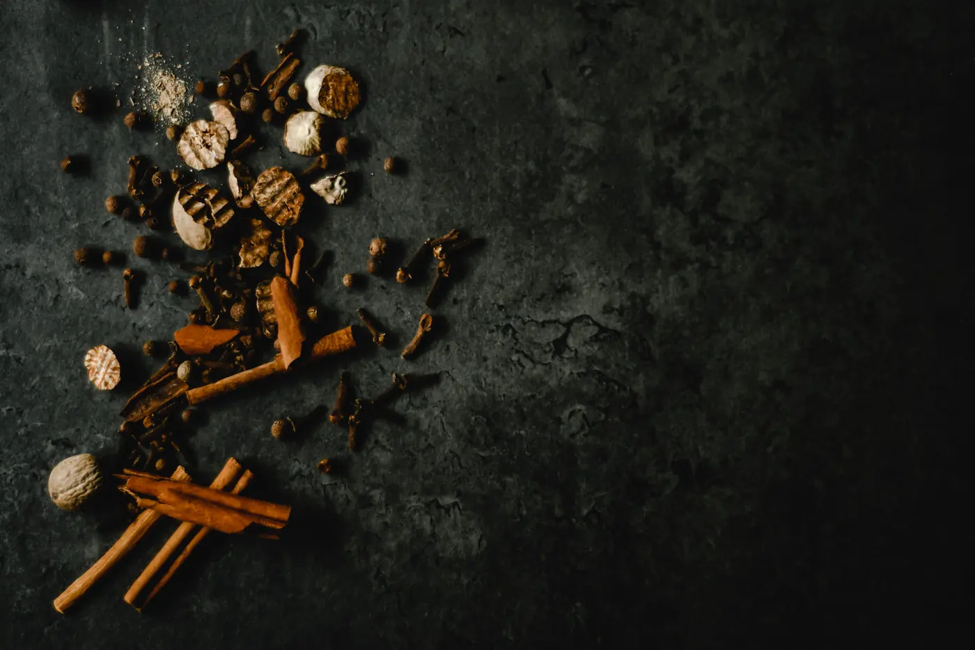 Whole spices laid out on a dark surface