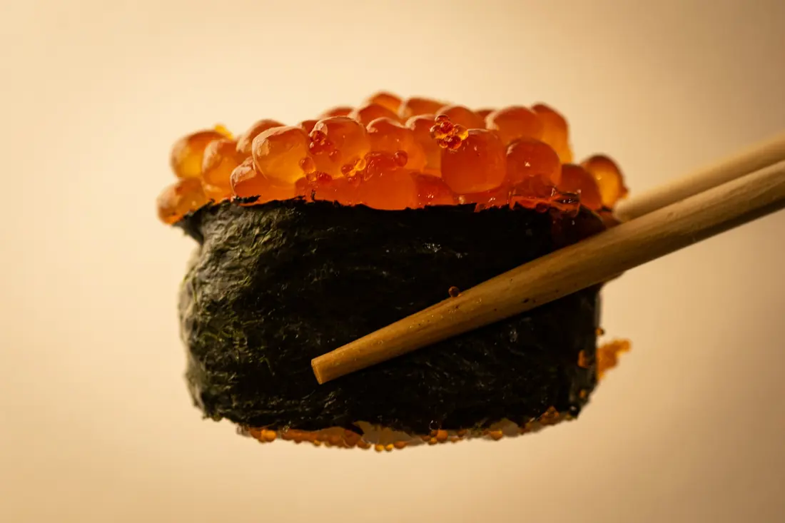 A piece of sushi topped with large orange roe