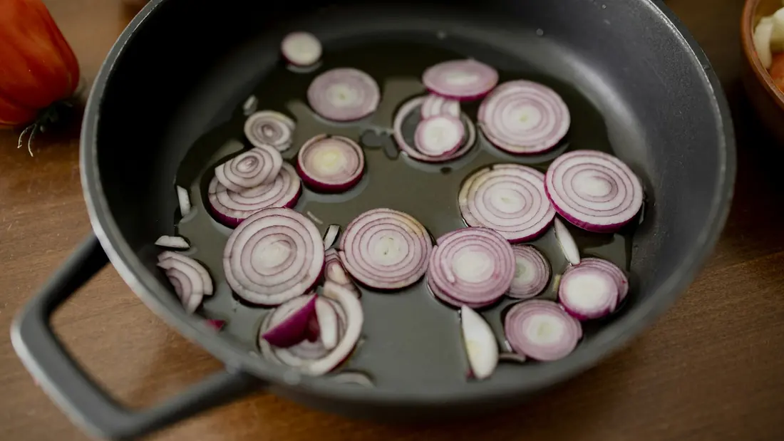 Sliced red onion in a pan before cooking