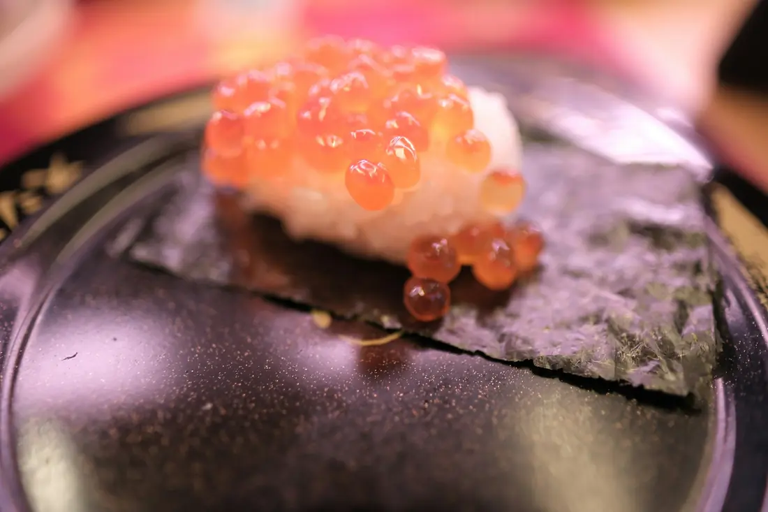 Large orange roe piled on a piece of sushi, close up