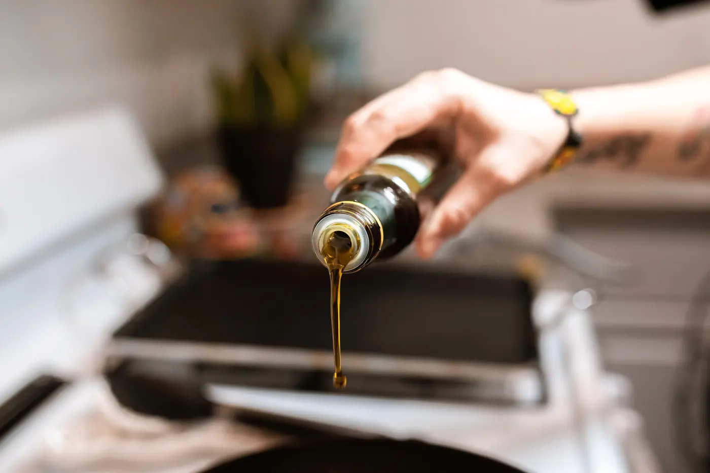 A liquid being poured from a bottle onto a hot surface