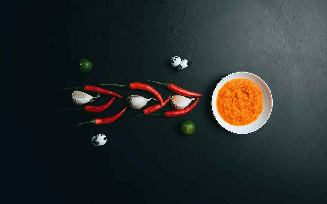 Fresh chillies beside a bowl of red chilli paste