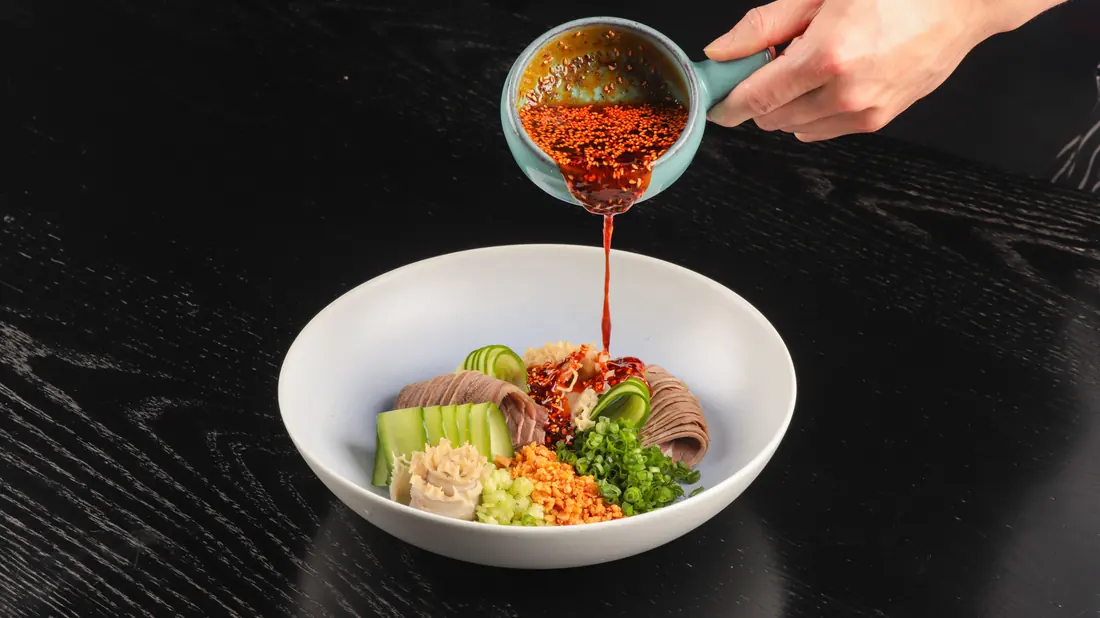 Chilli oil being poured over a bowl of food