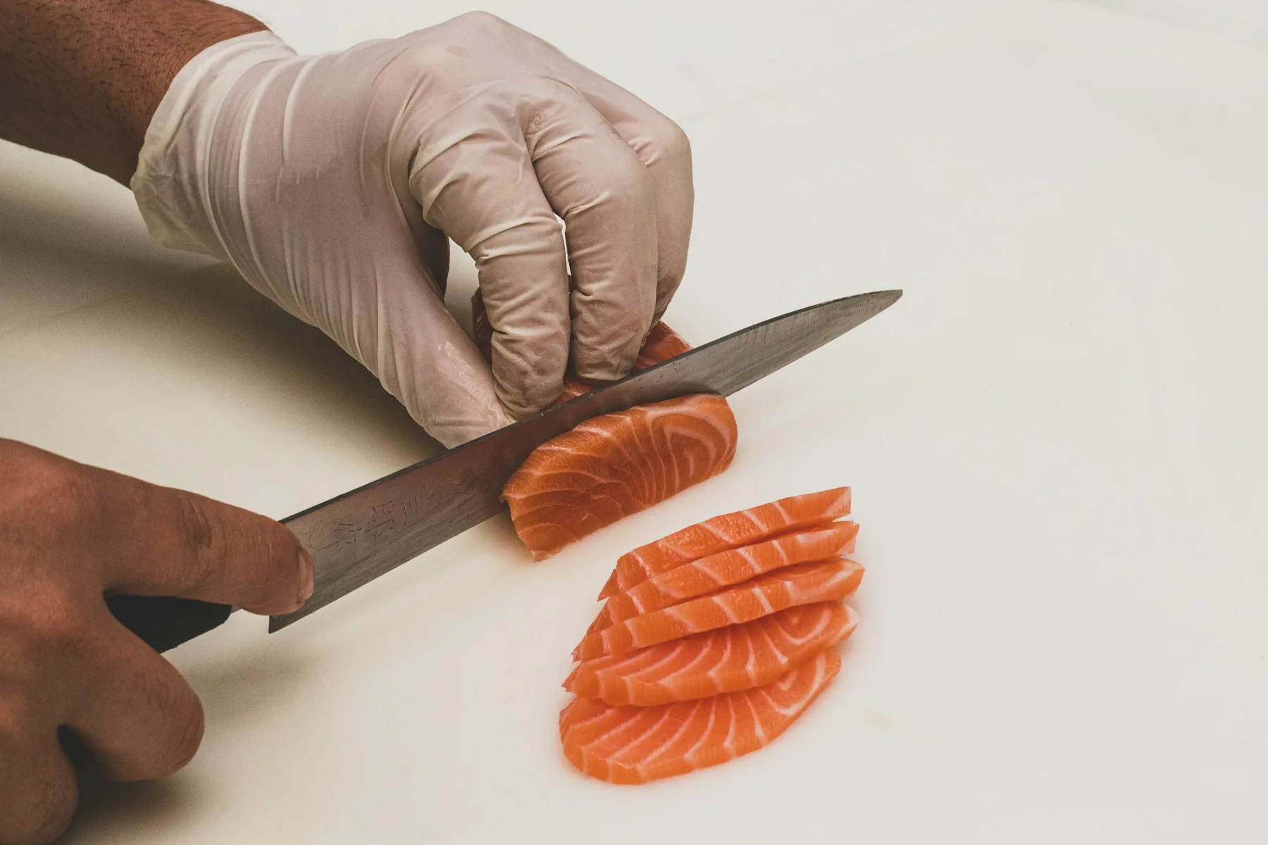 Sushi chef slicing fresh fish while preparing an order