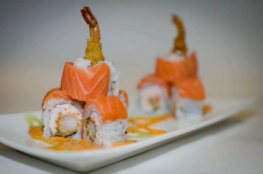 Geisha specialty roll - shrimp tempura and crab mix topped with fresh salmon
