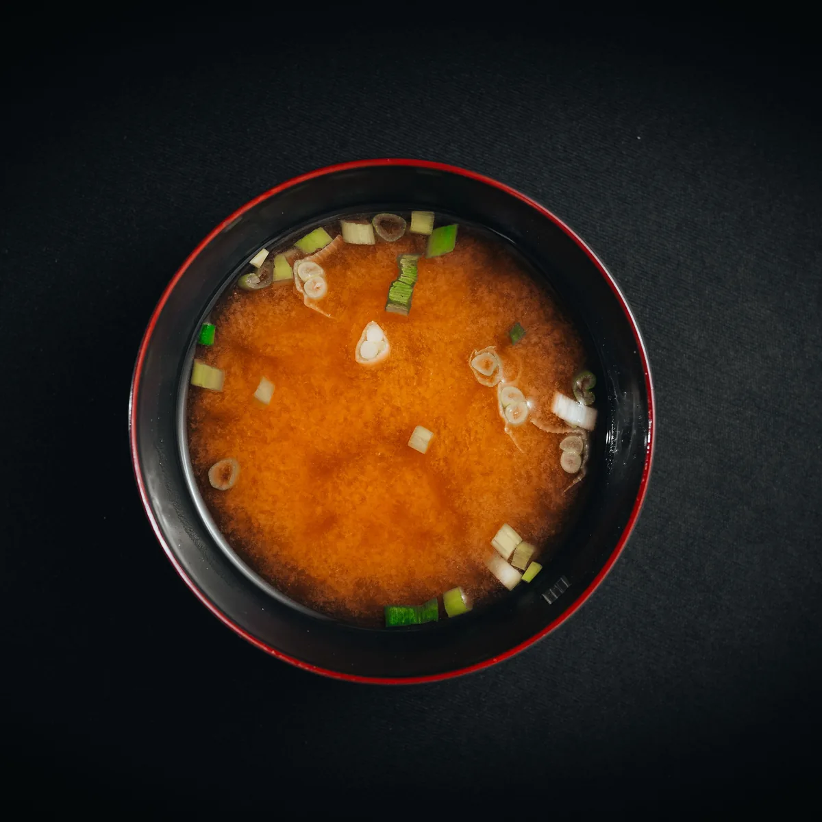 A bowl of miso soup with scallions, photographed from above