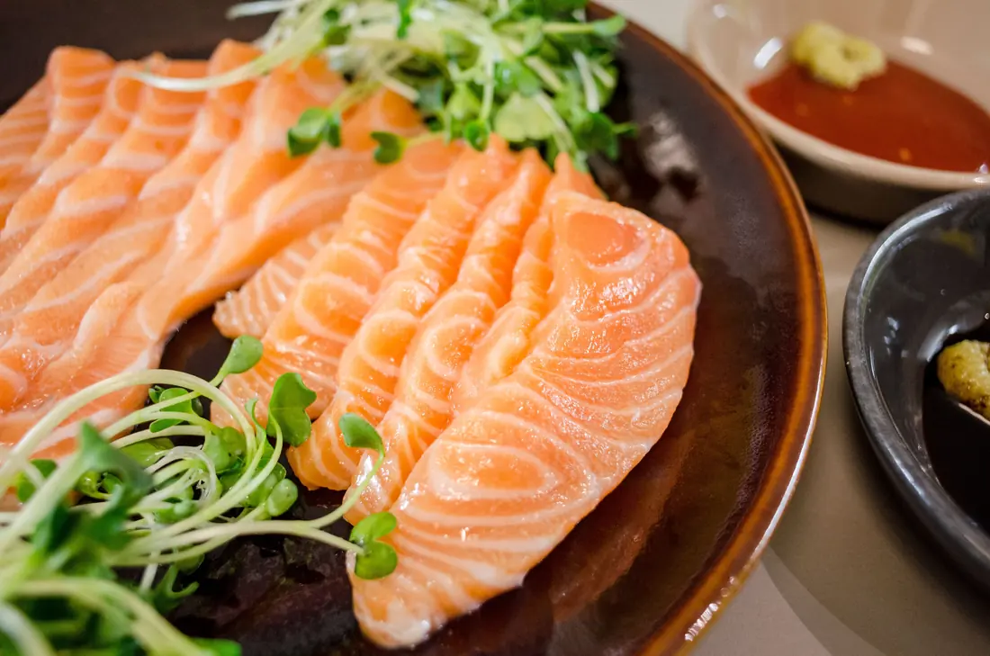 Sliced salmon sashimi fanned across a dark plate