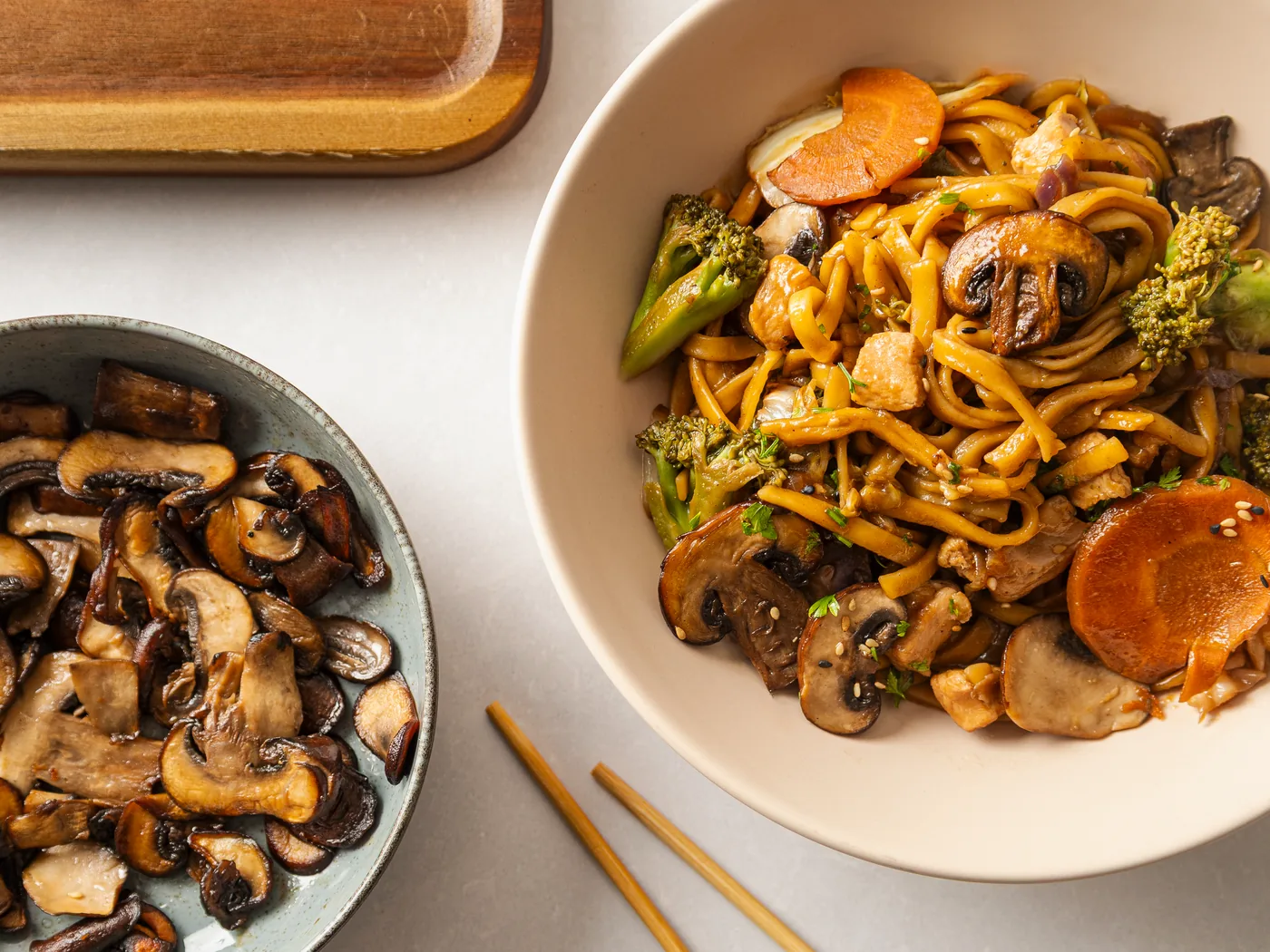 A bowl of stir-fried noodles with mushrooms, broccoli and carrot