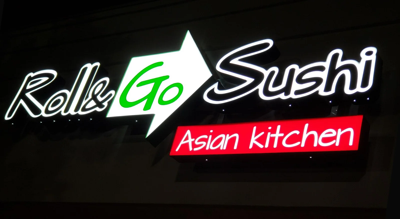 The illuminated Roll & Go Sushi Asian Kitchen storefront sign in Daphne, Alabama
