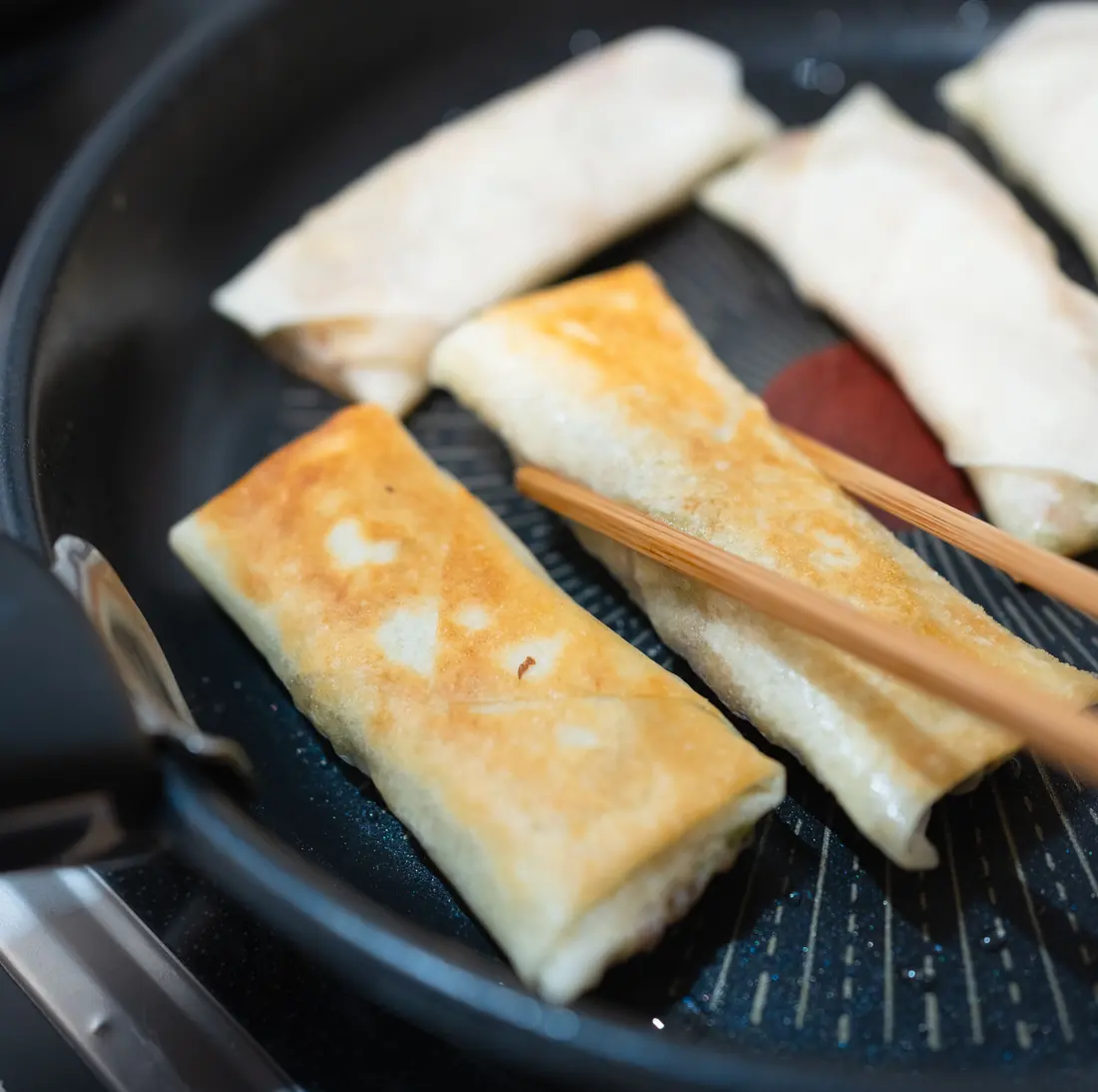 Rolled parcels browning in a pan
