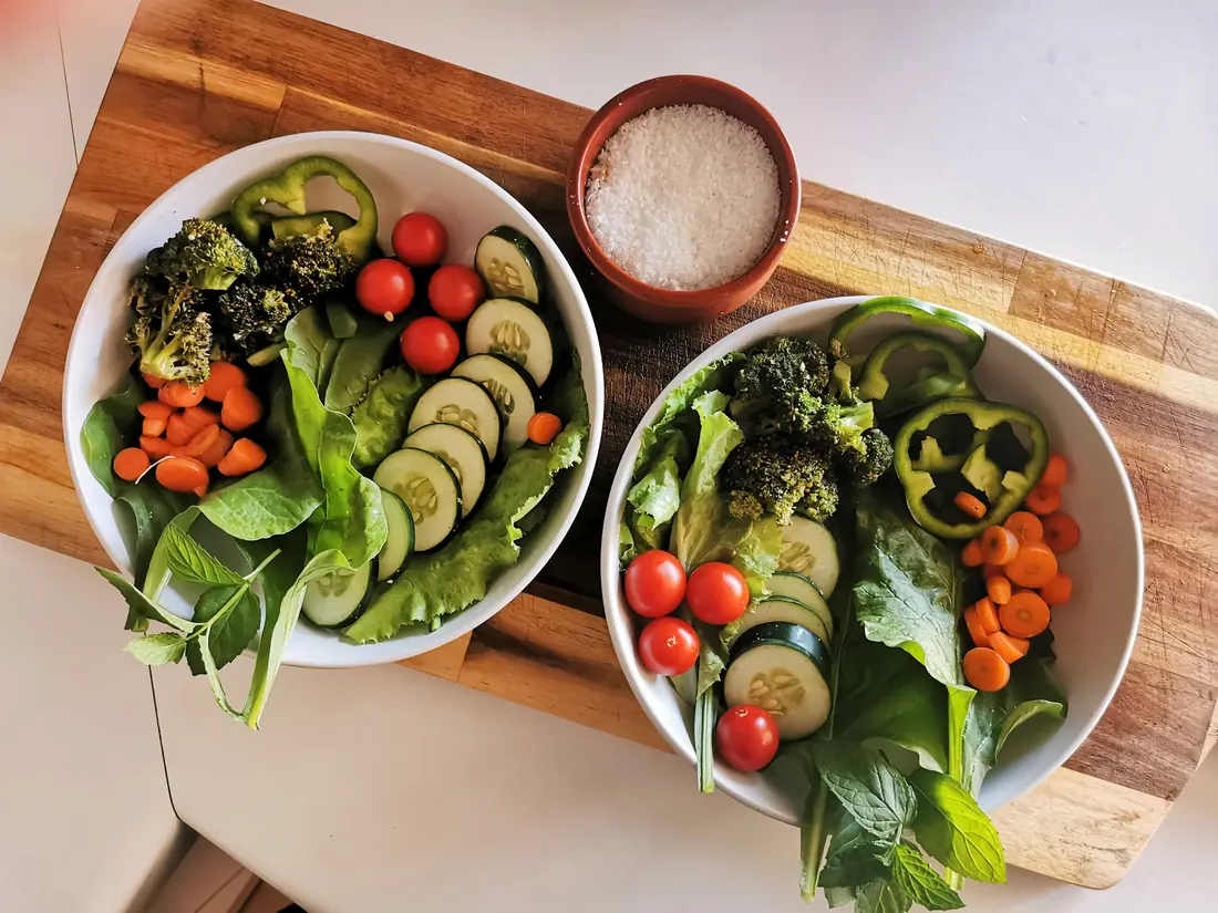 Bowls of vegetables beside a dish of salt
