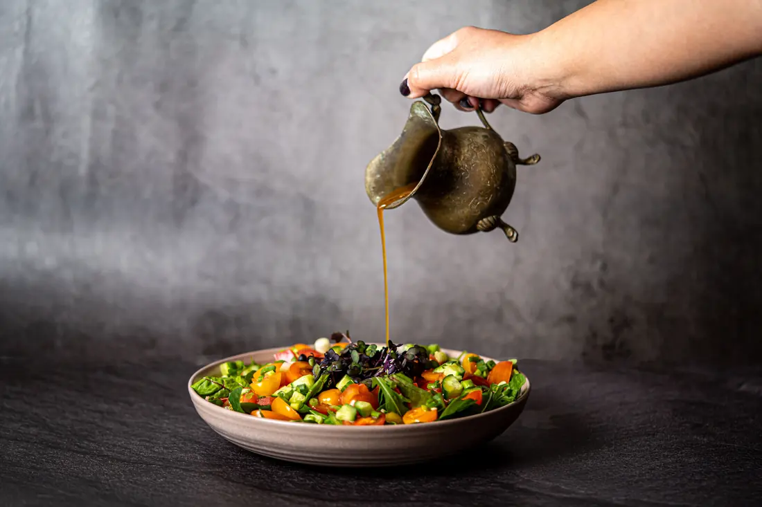 Sauce being poured over a vegetable dish