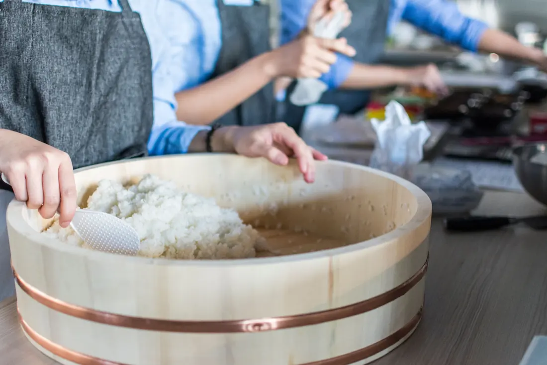 Rice being turned in a wide wooden tub