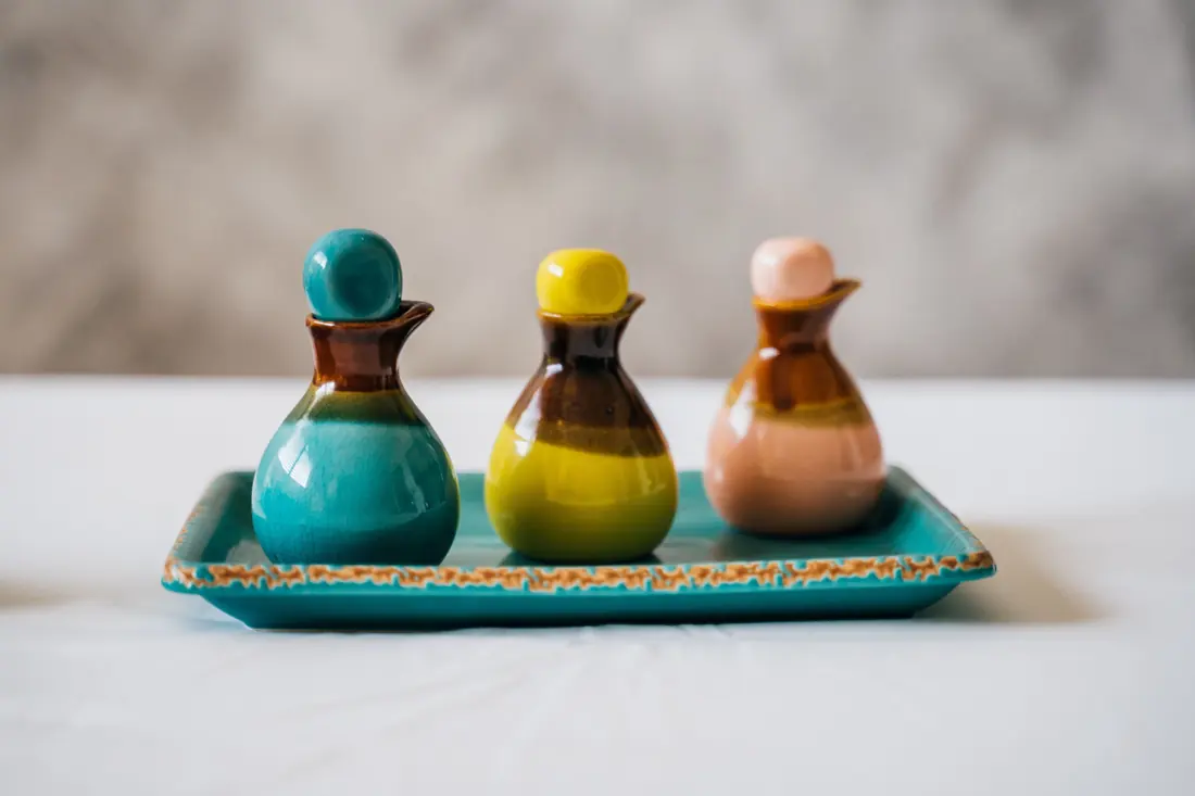 Small ceramic pouring bottles on a tray