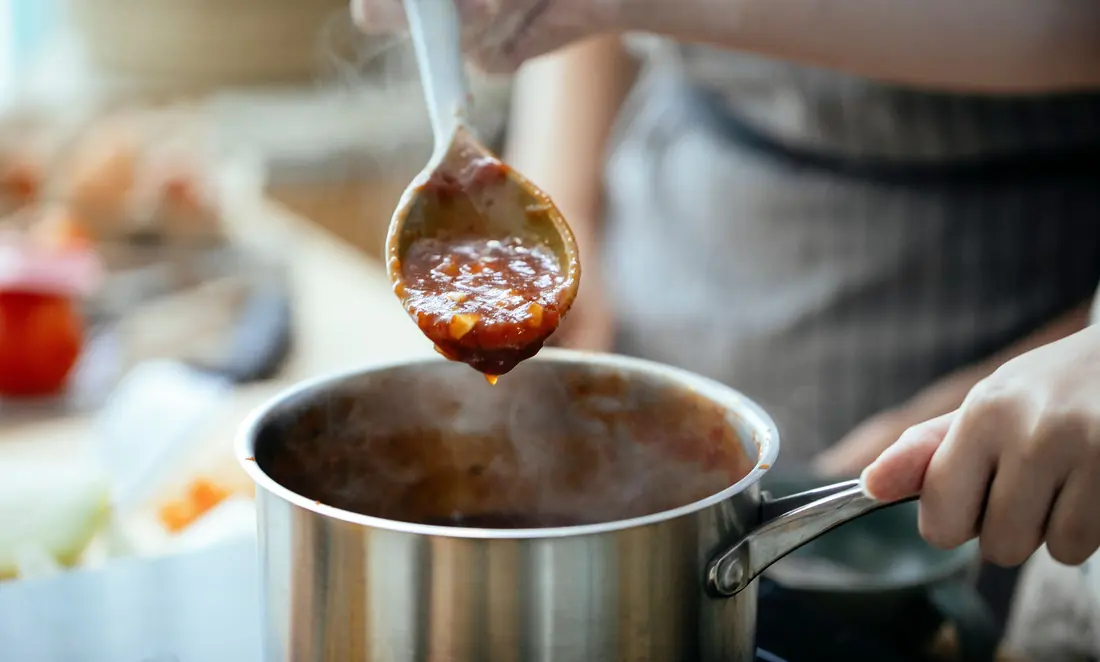 Sauce being lifted from a saucepan