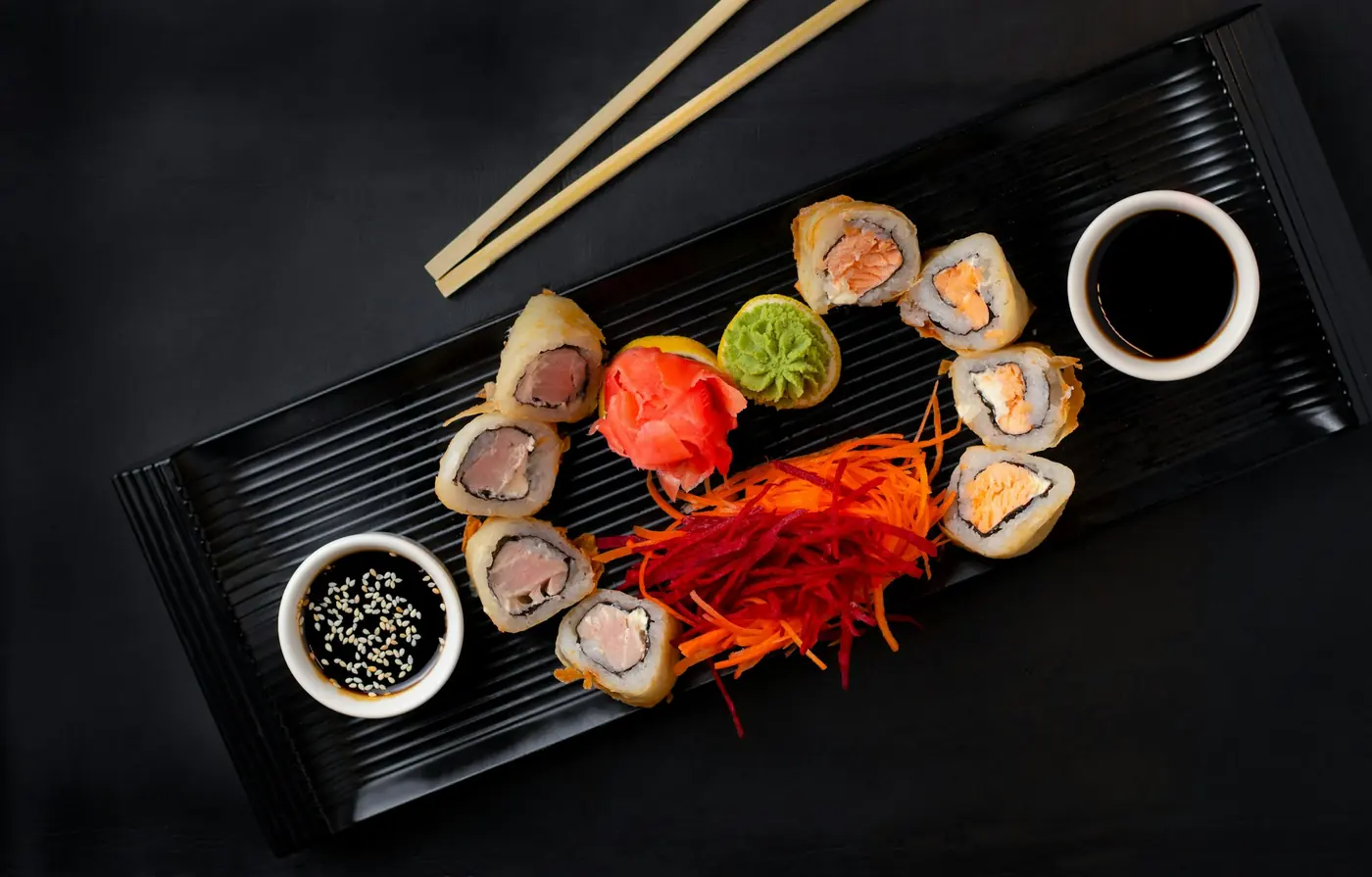 Specialty sushi rolls topped with fish and finishing sauces