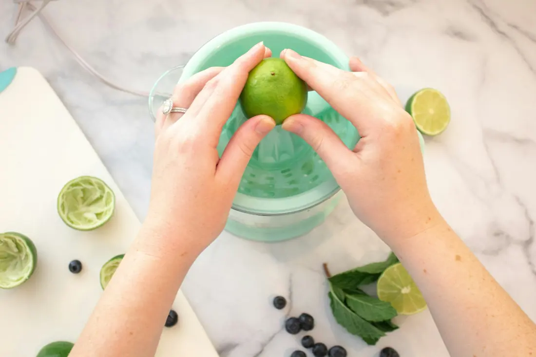 A lime wedge being squeezed into a bowl of noodle soup
