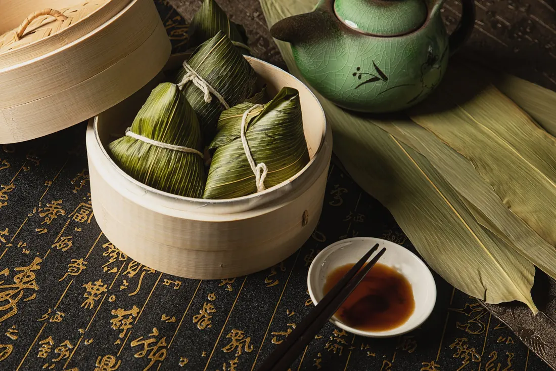 Leaf-wrapped rice parcels in a bamboo steamer