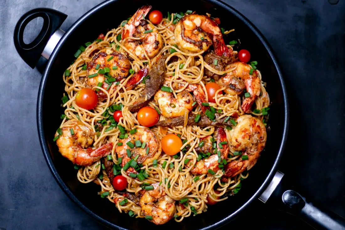 A pan of stir-fried noodles with shrimp and vegetables